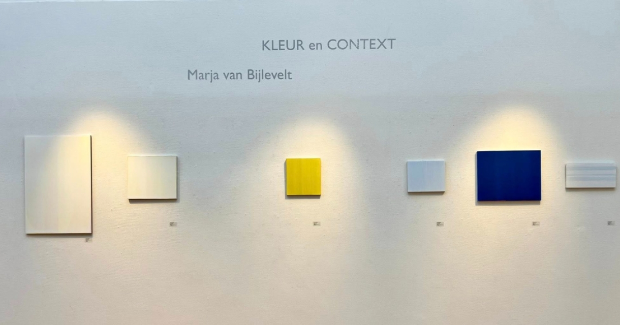 Vijf schilderijen in verschillende kleuren aan de muur.