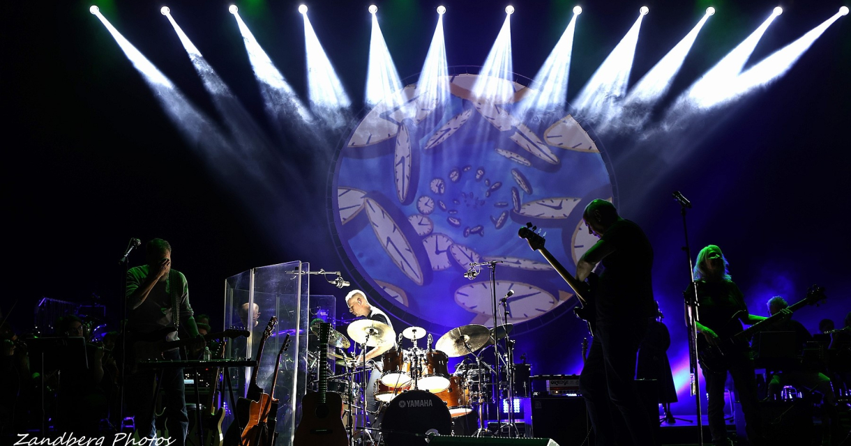 Een band speelt op een podium met felgroen en wit licht.