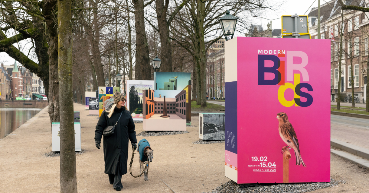 Frau mit Hund geht an Ausstellungstafeln vorbei.