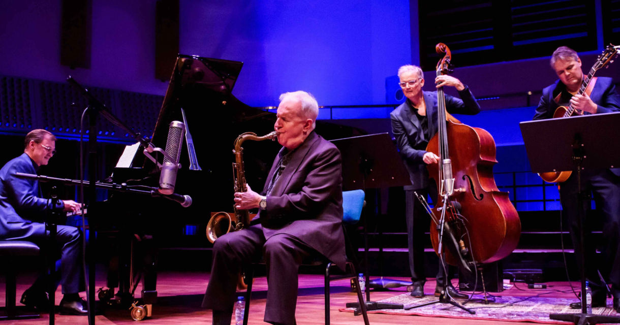 Vier muzikanten spelen jazz, inclusief saxofonist en pianist.