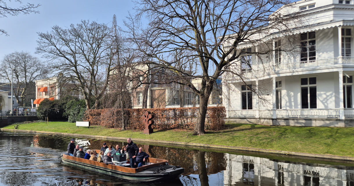 Groep mensen op een boot in een grachtenlandschap