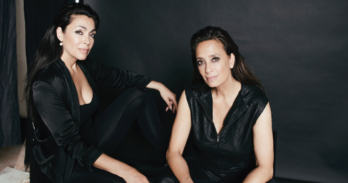 Twee vrouwen, gekleed in zwart, zitten in een studio.