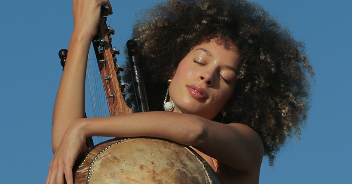 Een vrouw met krullend haar speelt op een snaarinstrument.