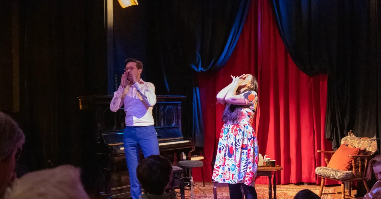A man and a woman performing with a piano in the background
