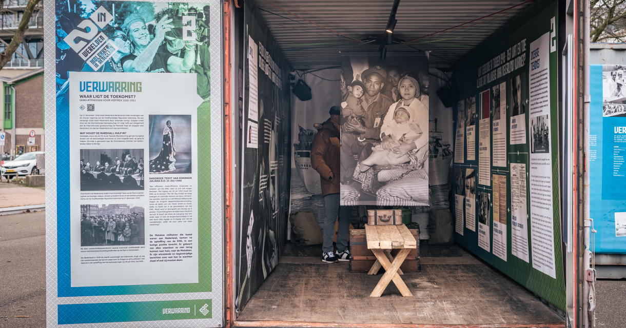 A man stands in a container with historical photos and information panels ‘75 Years of Moluccans in the Netherlands’.  Foto: Ed Leatemia