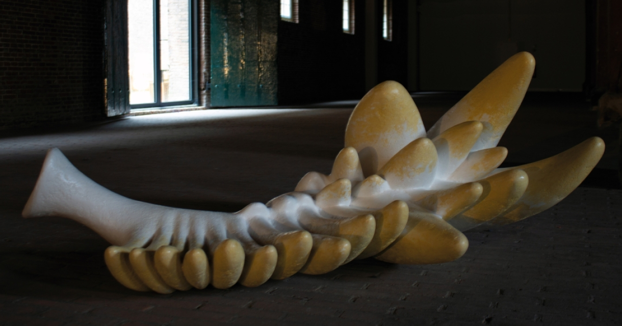 Yellow and white sculpture with wavy shapes in a dark space