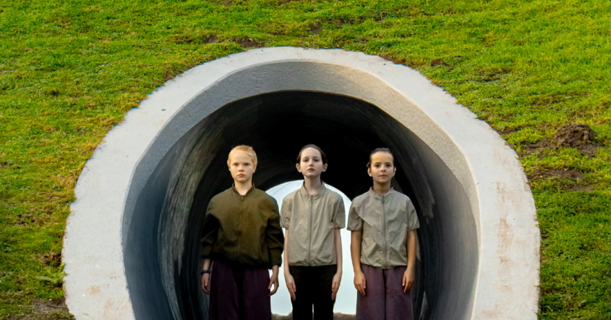 Drie kinderen staan in een tunnel op een grasheuvel.