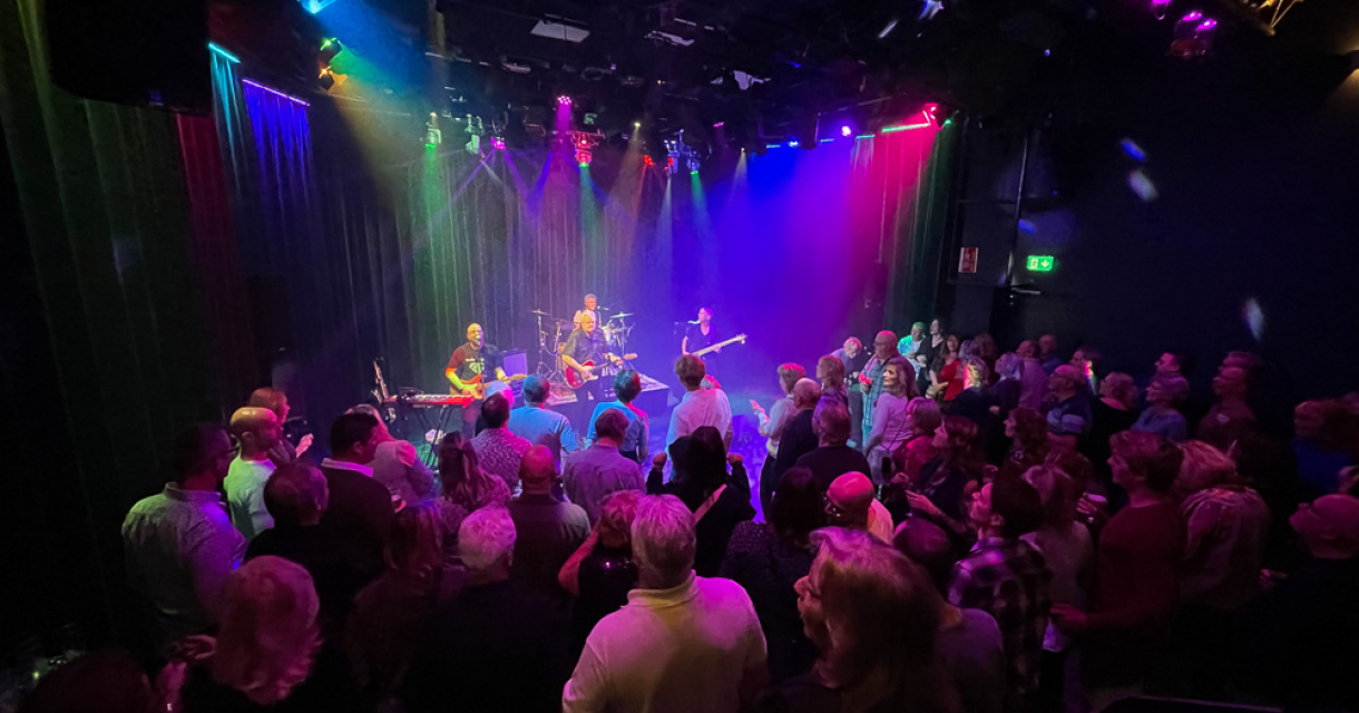 Muzikanten spelen op een podium voor een enthousiast publiek.