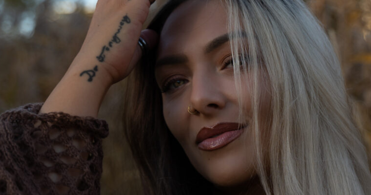 Vrouw met een tattoo die door haar haar strijkt