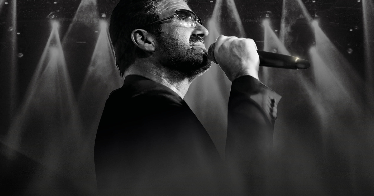 Man with a microphone singing under spotlights.