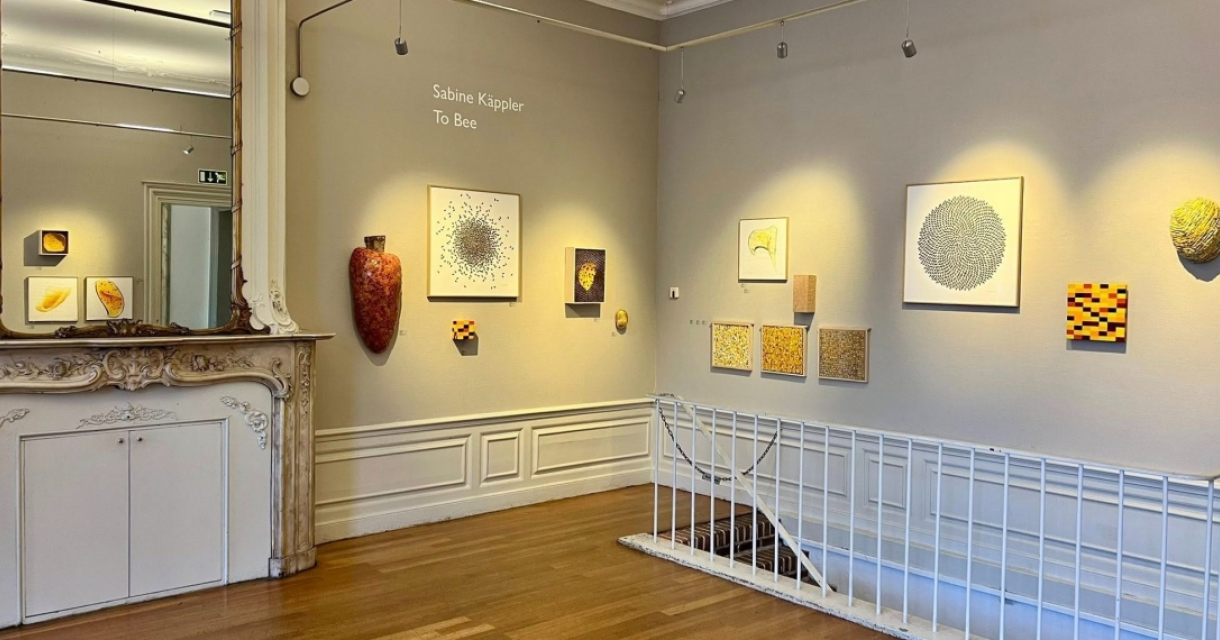 Interior of a gallery with abstract paintings on the wall.