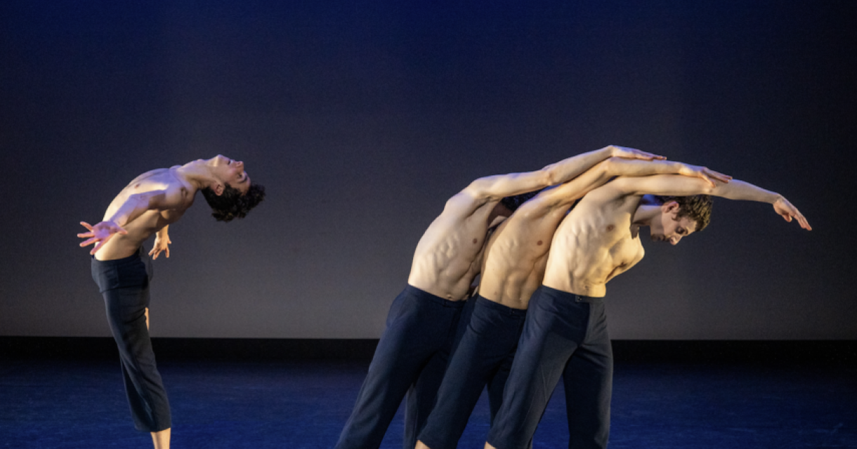 Vijf halfnaakte dansers in dynamische poses op een podium.