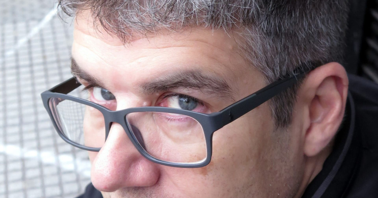 Man with gray hair and glasses, looking at the camera.
