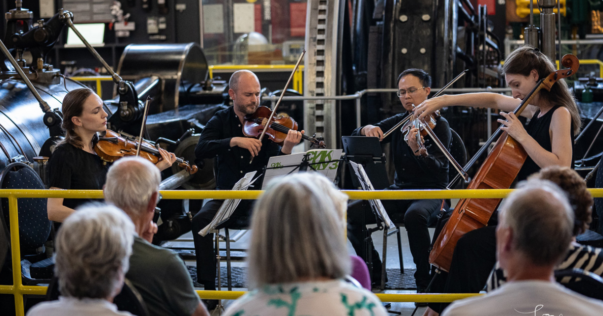 Musici spelen een klassiek concert in een industrieel gebouw.