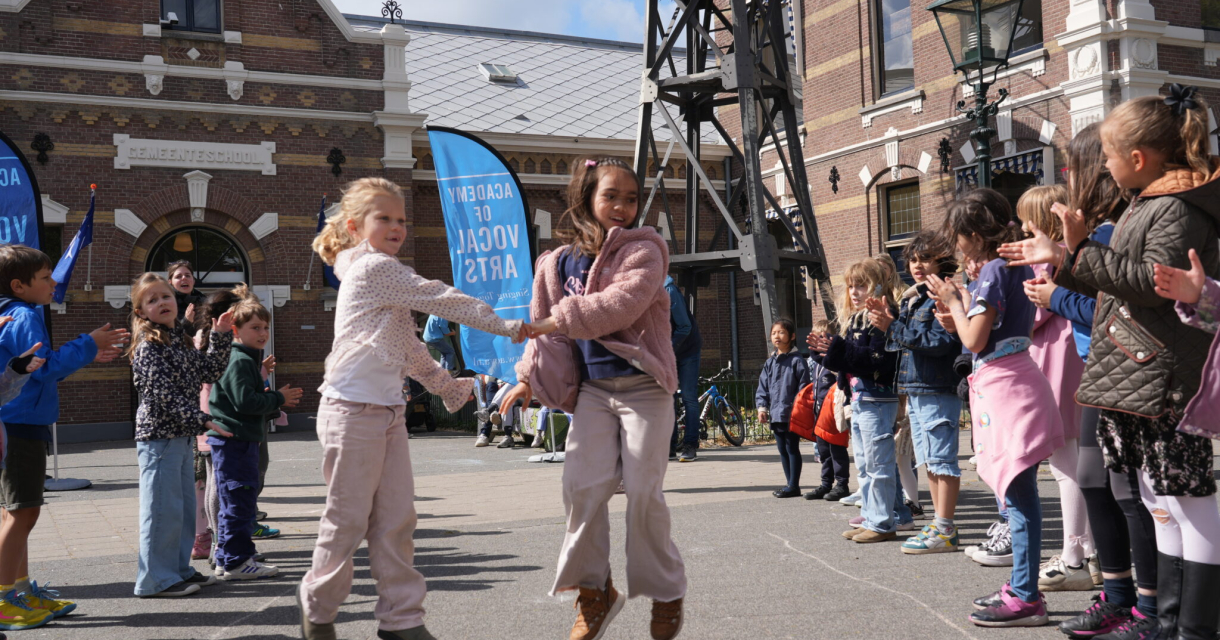 Kinderen springen en klappen in een cirkel, vrolijk en enthousiast.