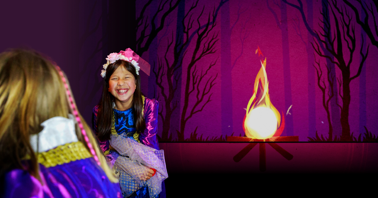 Gelukkig kind in kostuum met bloemen in haar haar bij een vuur.