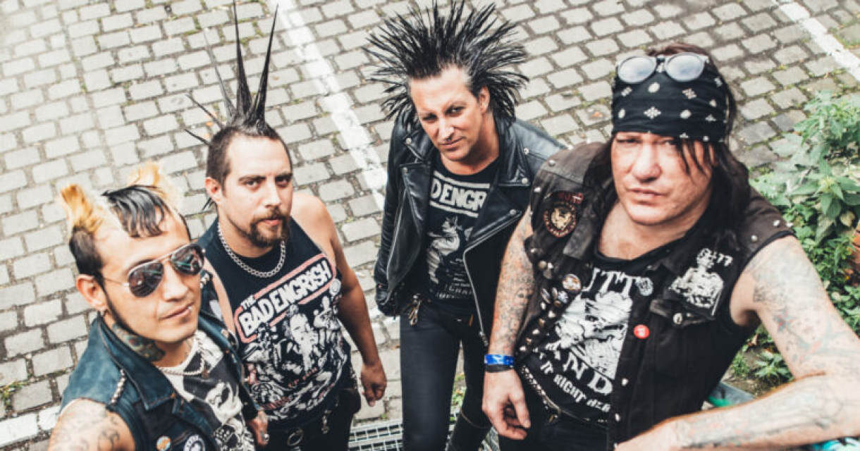 Vier leden van een punkband poseren buiten.