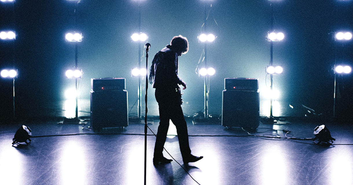 Silhouet van een muzikant met een gitaar, omgeven door lichten