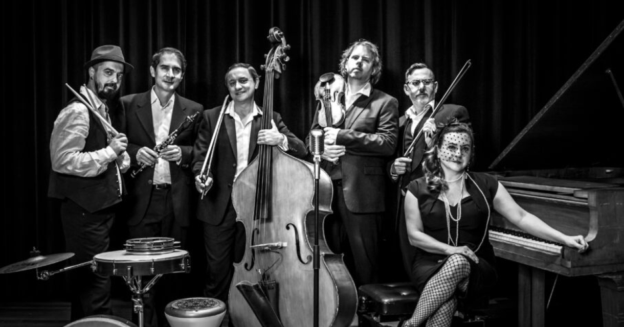 Groep muzikanten met diverse instrumenten in zwart-wit.