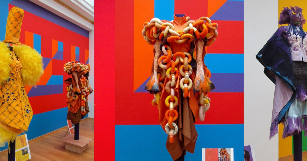 Drie modeontwerpen in felle kleuren op standbeelden.