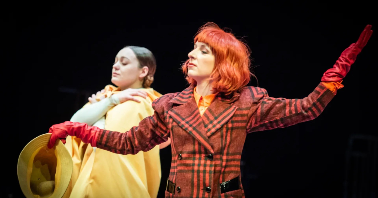 Twee acteurs in kleurrijke kostuums op een podium.
