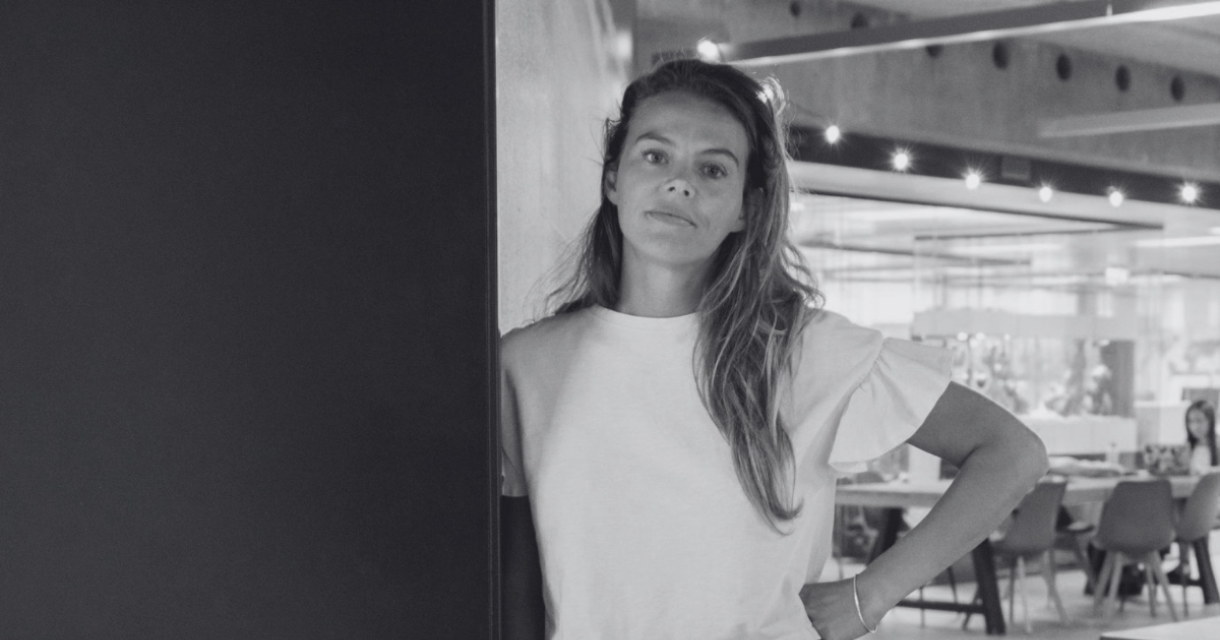 Een vrouw in een wit shirt en zwarte rok staat naast een box met 'buzbo x The Hague Tech'.