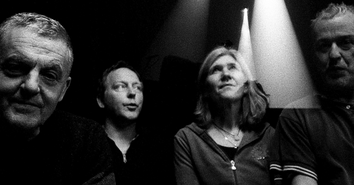 Groep mensen in schaduw. Vier mensen in het donker, hun gezichten verlicht door een lichteffect.