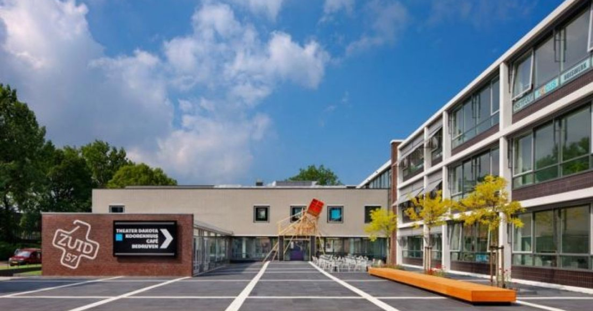 Moderne buitenaanzicht van Theater Dakota in Den Haag met groene bomen.