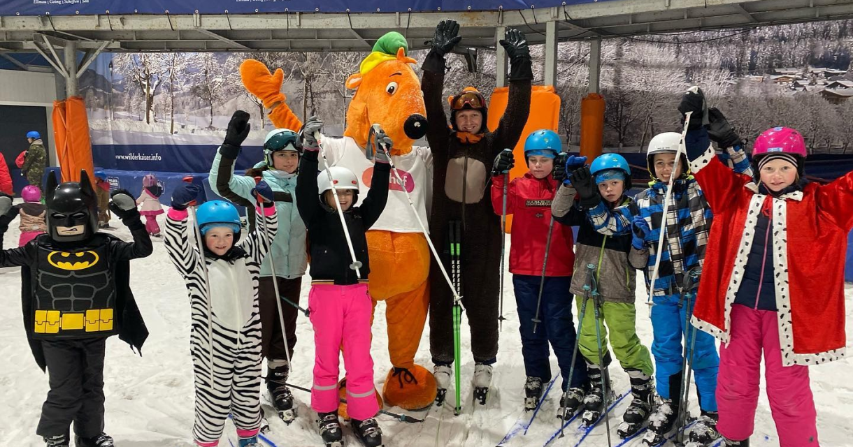 Een groep kinderen in skikleding poseert op een skipiste.