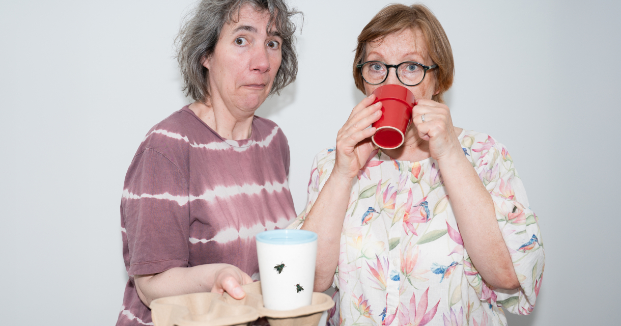 Twee vrouwen met bekers en verbaasde gezichten Twee vrouwen met bekers en verbaasde gezichten