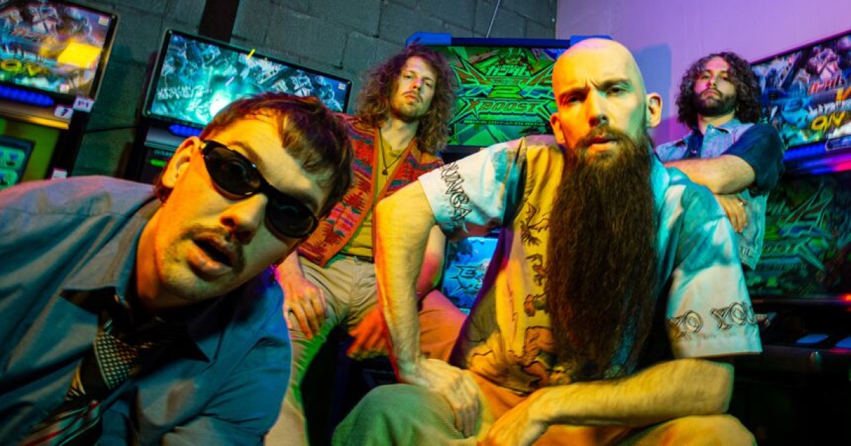 Psy-garagepunkband Wasted Youth Club poseert in een gameroom en kijkt nonchalant in de camera.