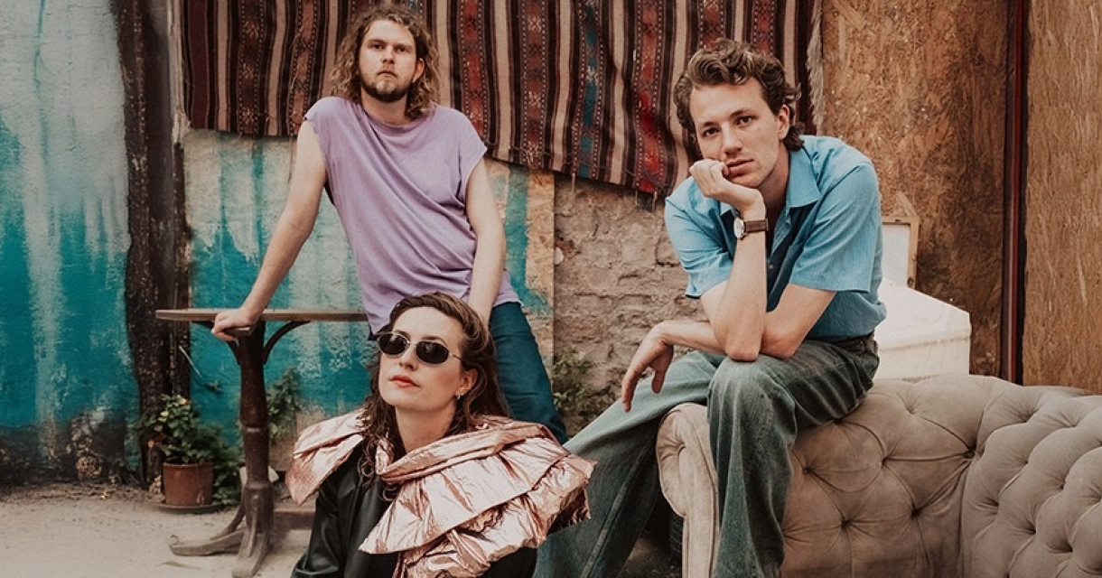 Drie muzikanten poseren met kleurrijke achtergrond