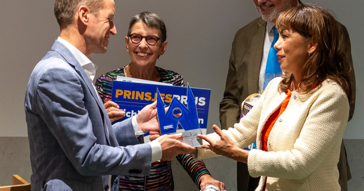 Een groep mensen geeft een prijs tijdens een ceremonie.