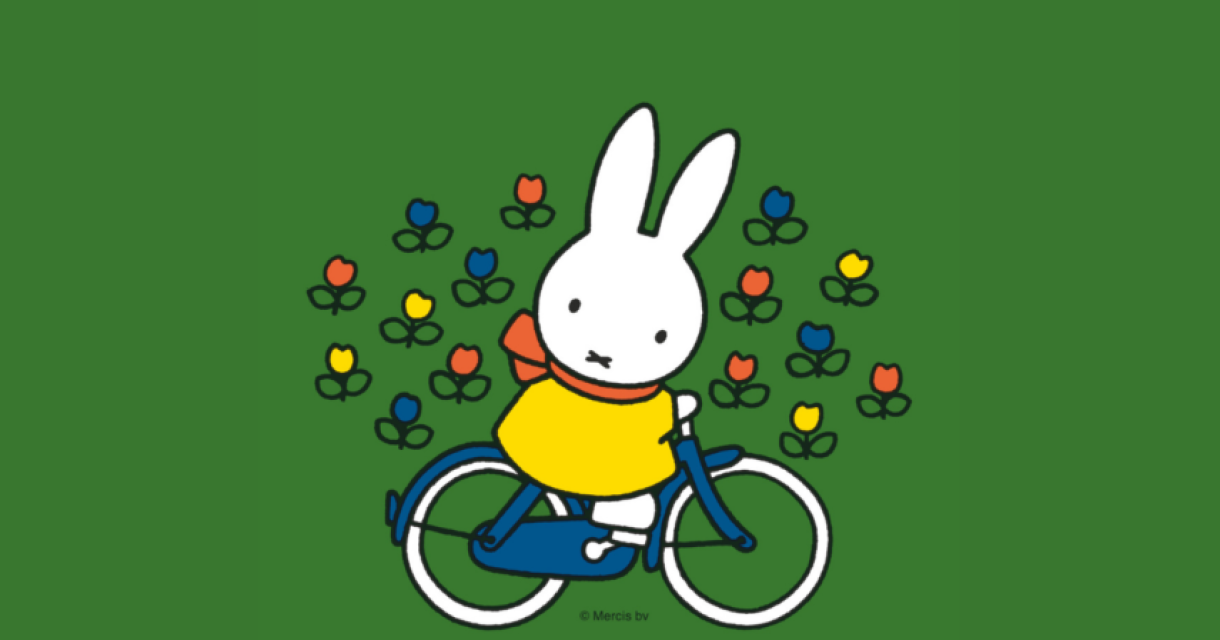 Nijntje in een gele trui fietst tussen bloemen.