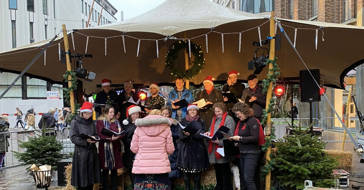 Een kerstkoor verleent een optreden onder een tent in Den Haag.