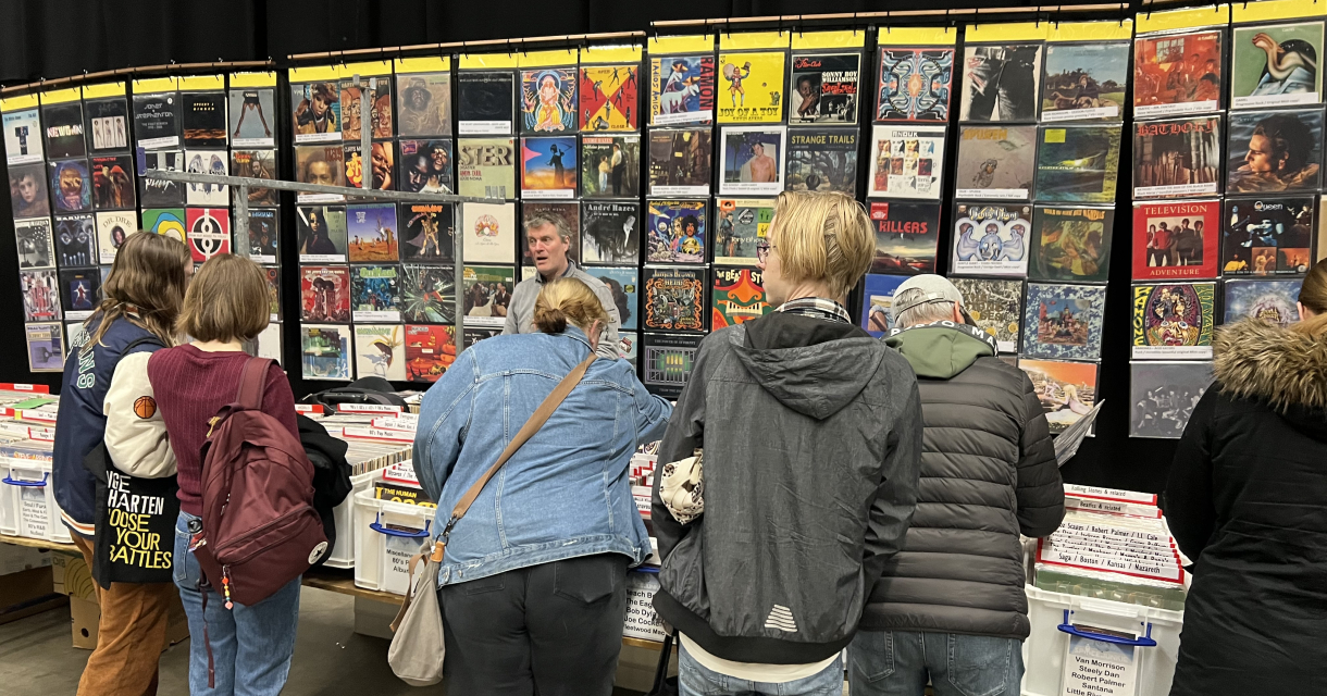 Bezoekers bekijken vintage vinylplaten op een beurs.