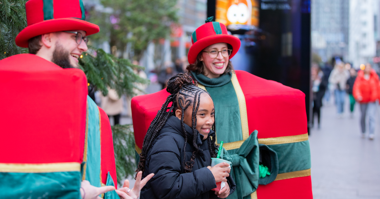 Een meisje poseert met verklede kerstfiguren in Den Haag.