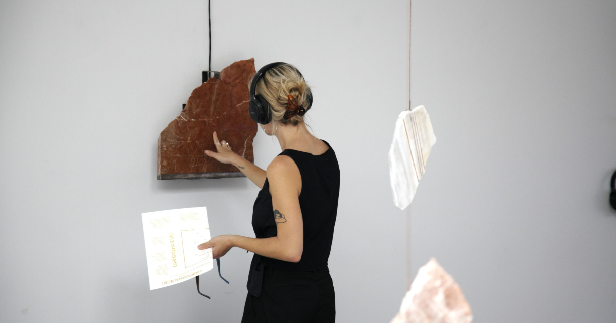 Vrouw met koptelefoon werkt aan en kunstwerk in een lichte ruimte