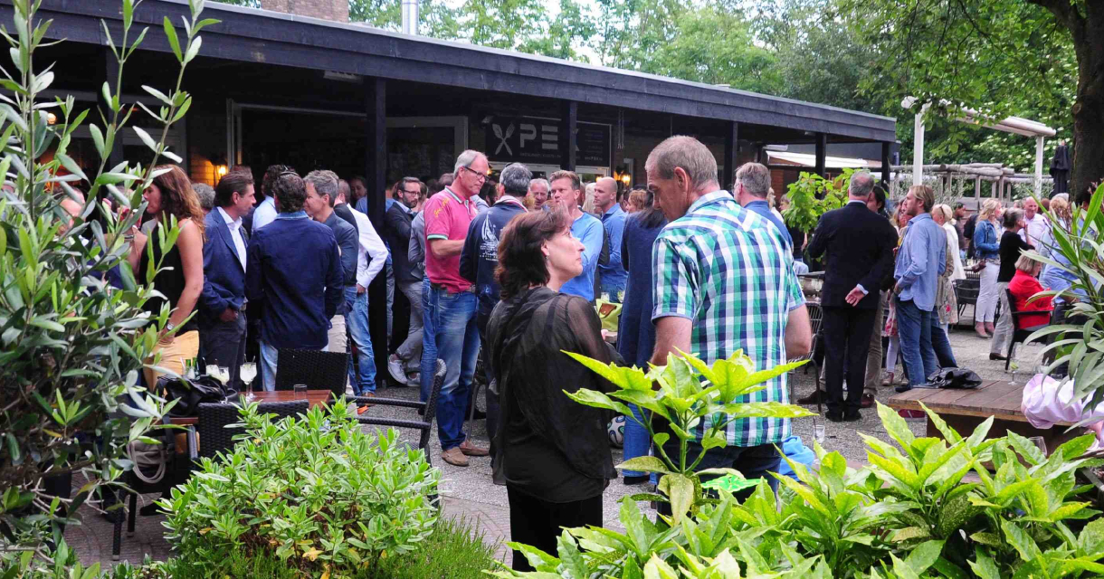 Mensen staan te kletsen op het groene terras van restaurant Pex