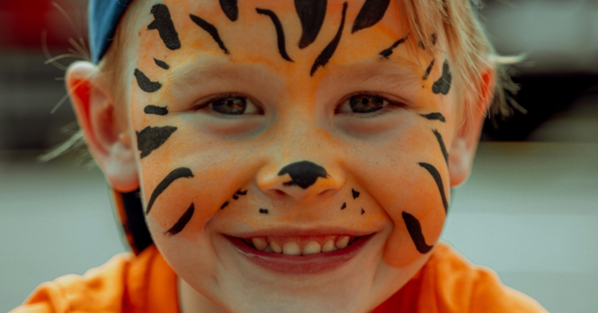 Blije jongen met tijgergezichtsverf en oranje shirt