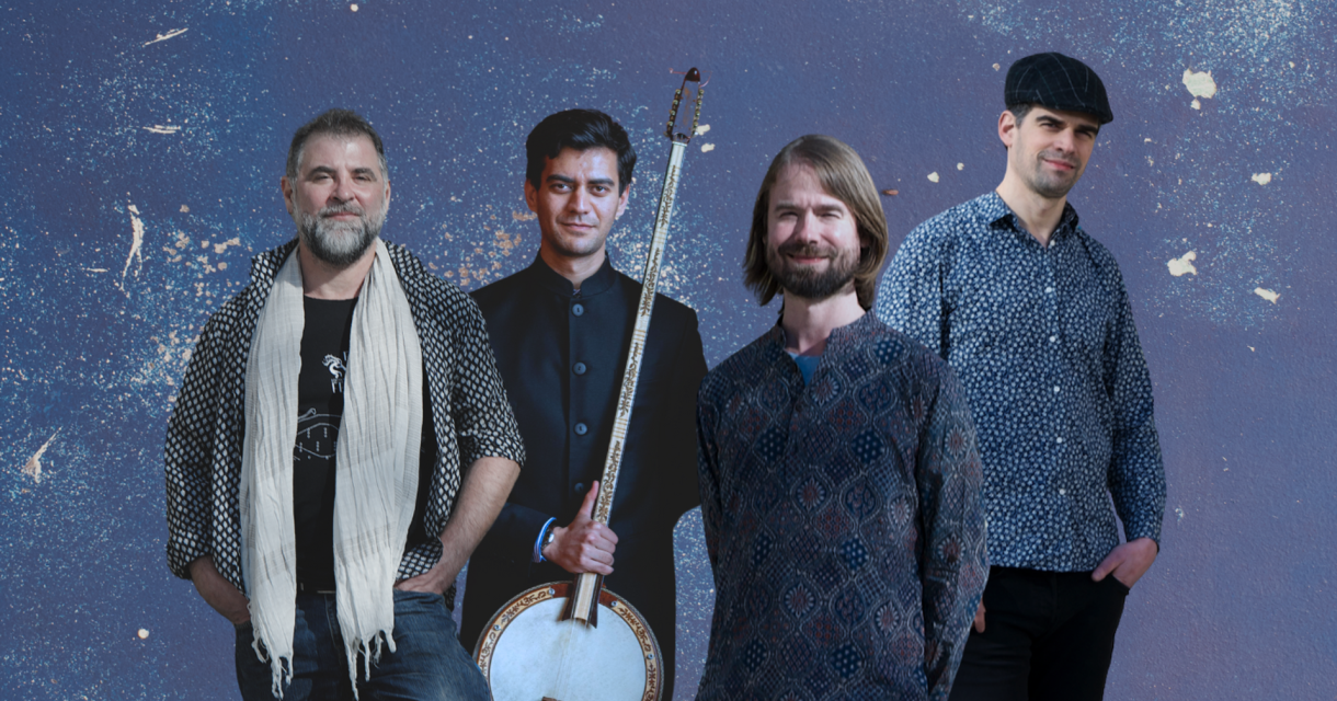 Vier mannen poseren voor paarse achtergrond, één met banjo, gekleed in casual tot artistieke kledingstijl