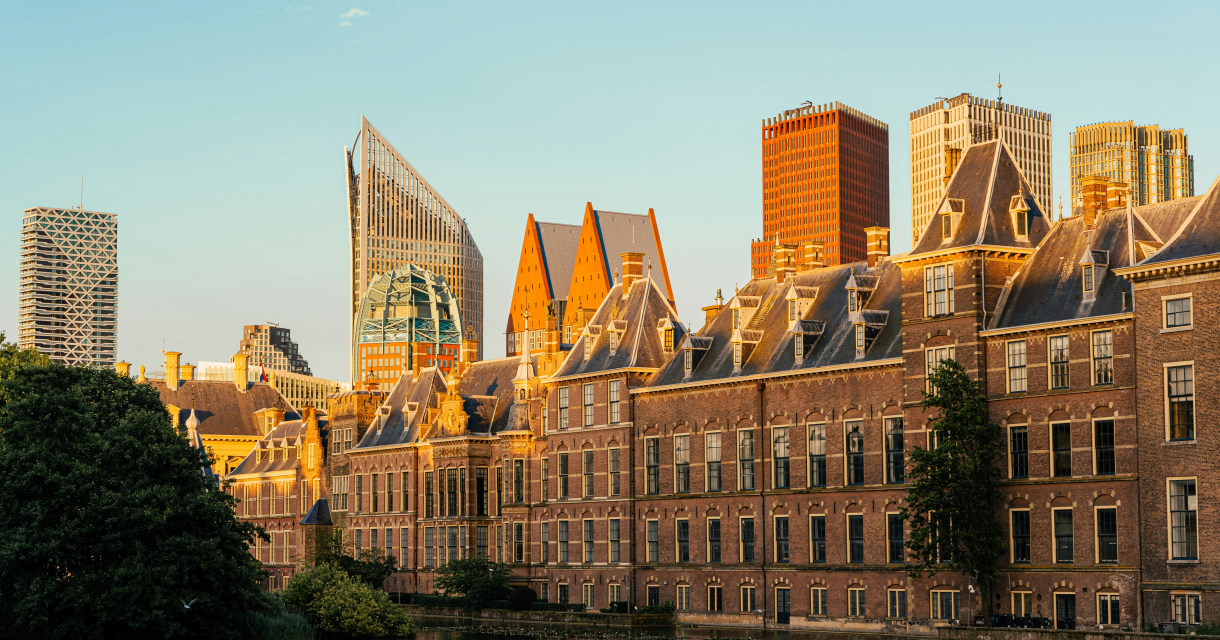 Het Binnenhof en de Hofvijver gefotografeerd in de avondzon met op de achtergrond de moderne skyline van Den Haag