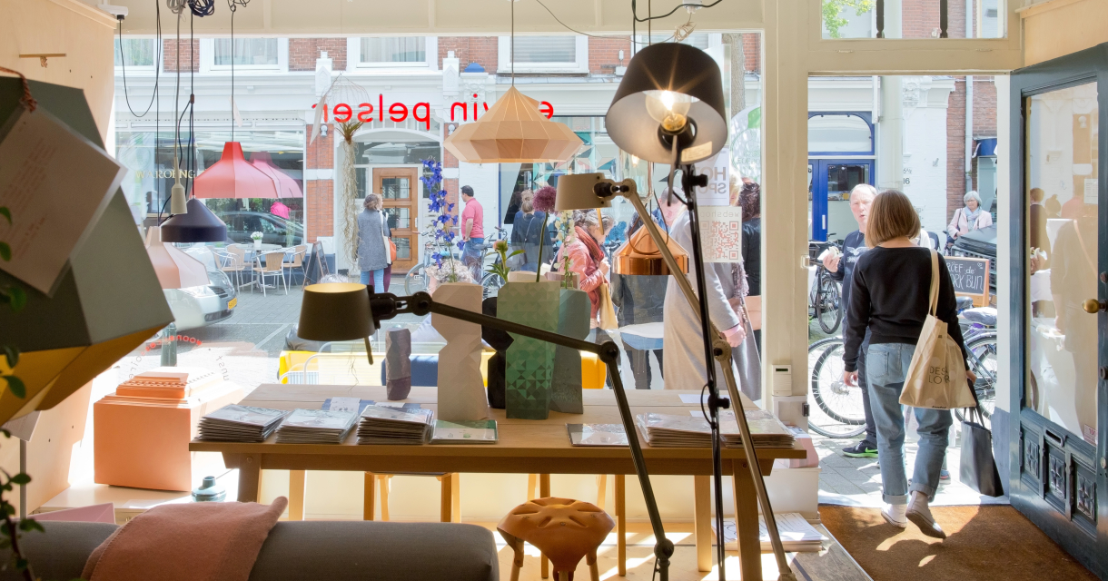 Een blik op een winkelinterieur met lampen en mensen buiten.