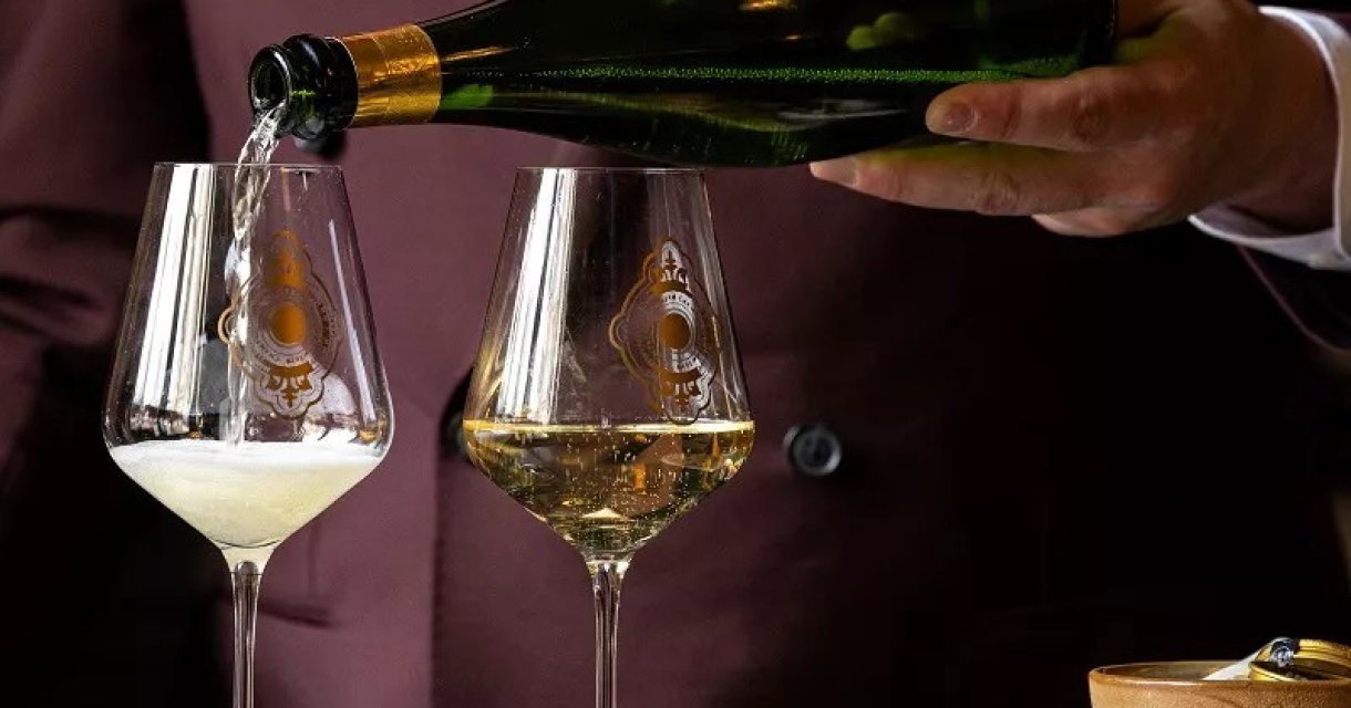Hand van een man die champagne in twee glazen schenkt