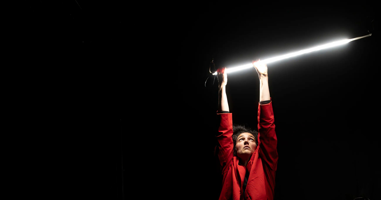 Een persoon in een rode outfit houdt een lichtbalk omhoog.