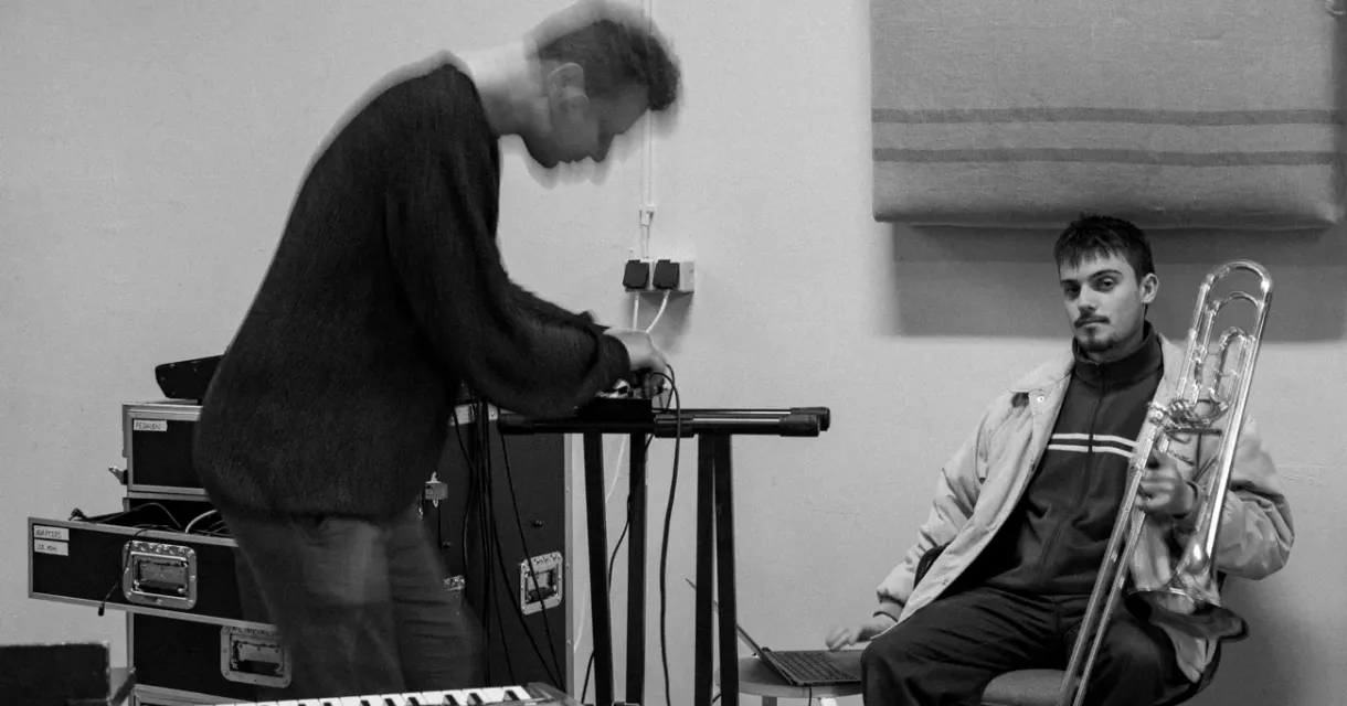 Two musicians: one playing and the other with a trombone.