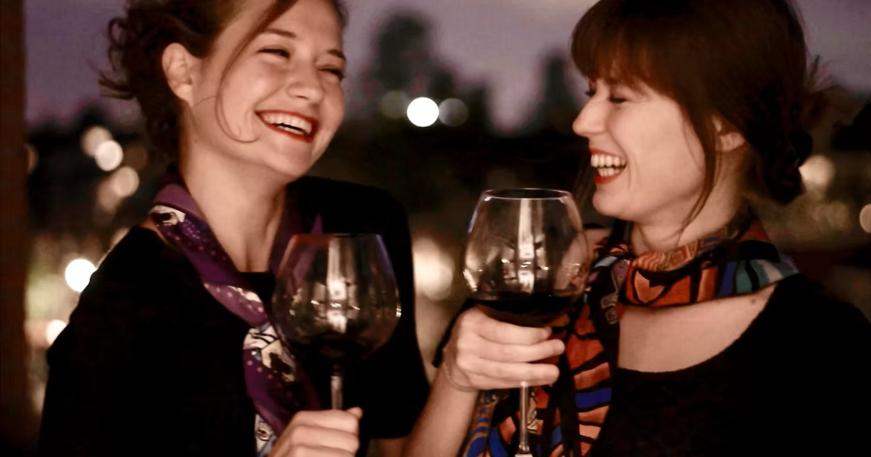 Twee lachende vrouwen met rode wijn in hand