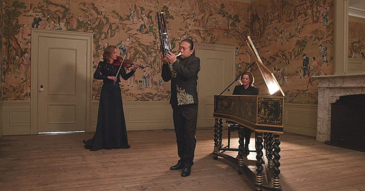 Drie muzikanten spelen klassieke muziek in een stijlvolle ruimte.