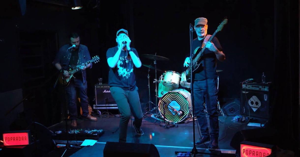 Vier muzikanten spelen live muziek op een podium.