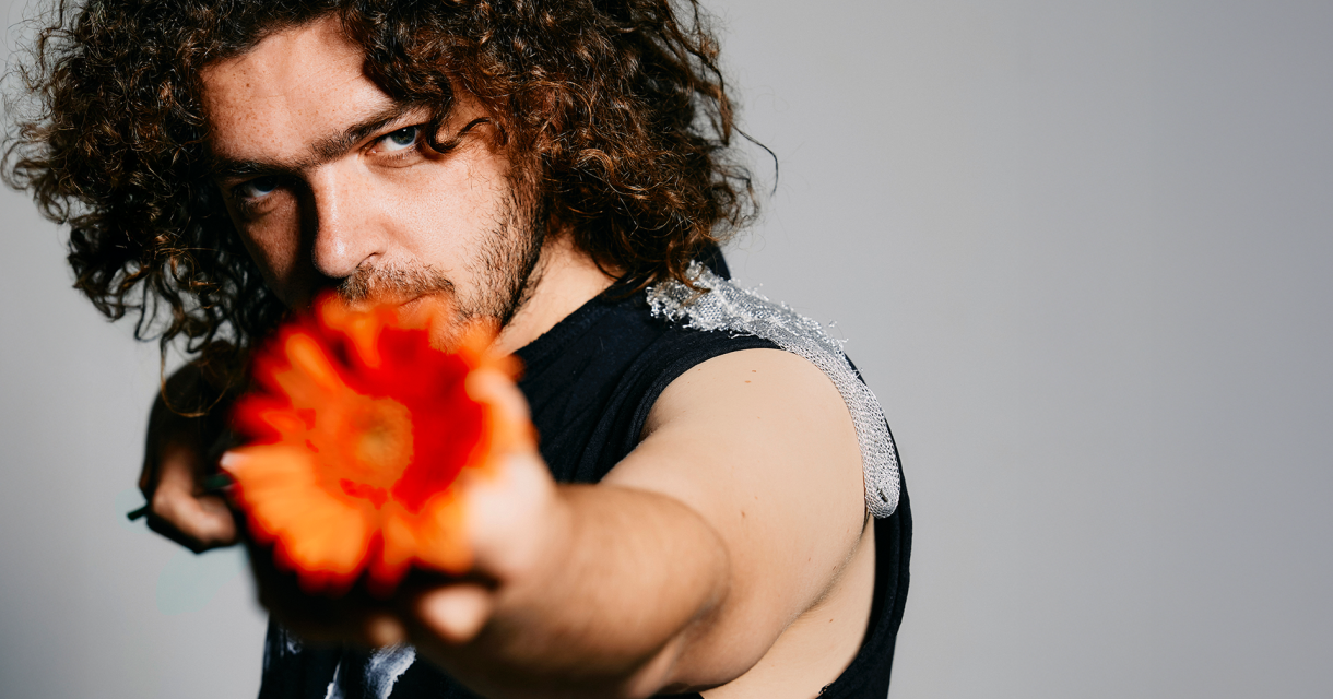 Een man richt een oranje bloem naar de camera.